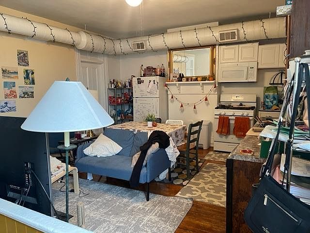 Kitchen Equipped with Additional White Cabinets, Built-In Microwave, Stove & Refrigerator, & HVAC Ductwork