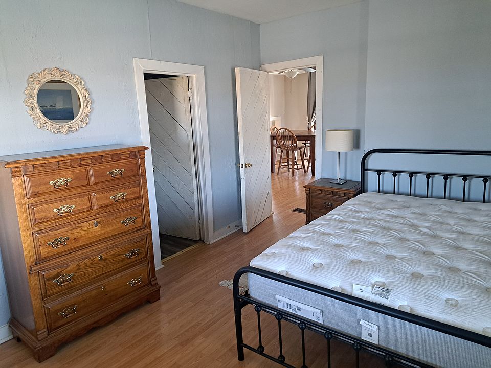 Large bedroom with queen bed, two dressers, and a walk in closet.