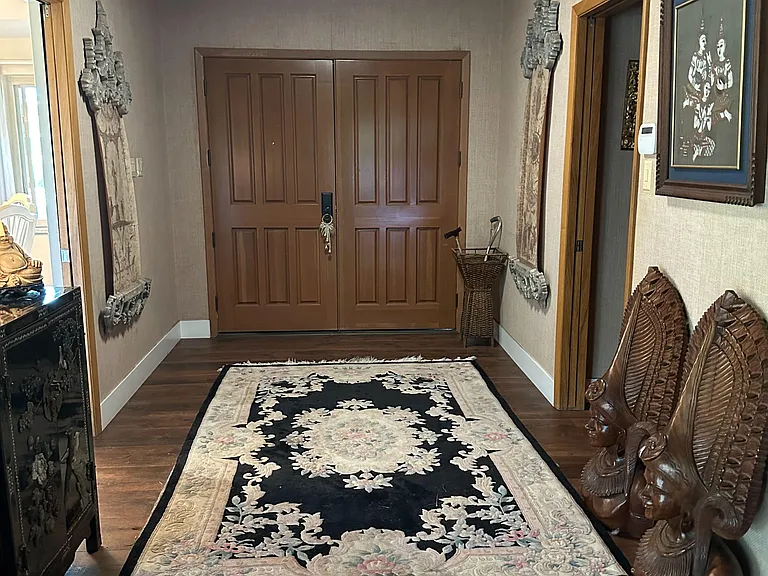 Welcoming entry foyer with durable wood-look flooring, wide double doors, and a runner rug offering space for drop-zone stora
