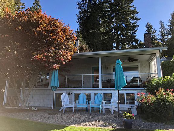 Front patio facing West to the Bay with Adirondack chairs and large umbrellas.