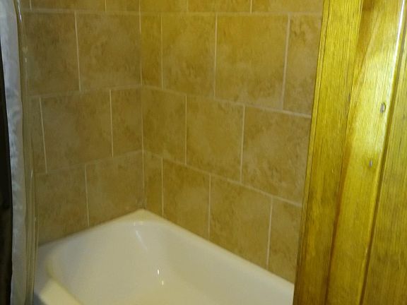 Nice new bath tub and new porcelain tile with new plumbing fixtures. Color of tile looks darker than it is. Very nice light color