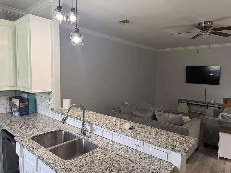 Open-concept kitchen with granite-look counters, breakfast bar seating, and direct sightlines into the living area.