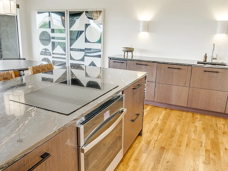 The sleek Bosch electric cooktop almost disappears from view when not in use. It is matched with a Bosch 500 series in-wall oven. A Faber venting system is out of view, flush with the ceiling when off.