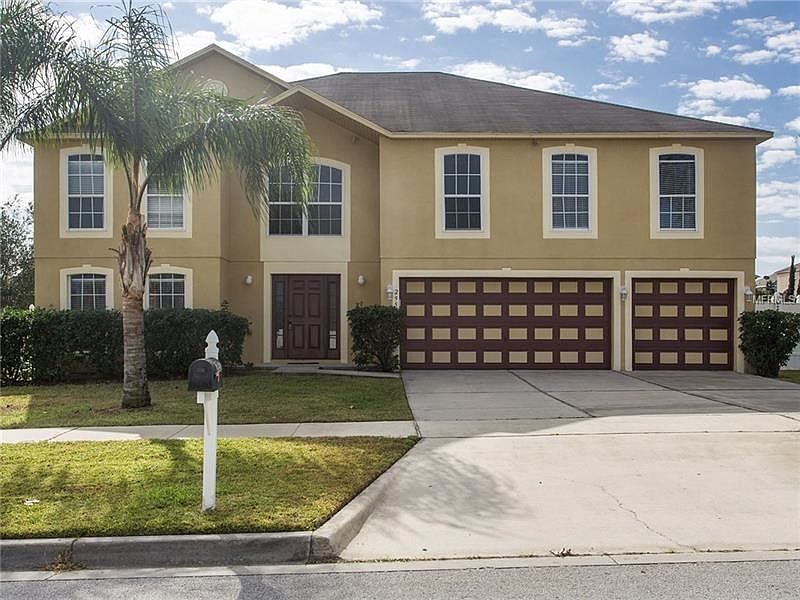 FRONT ELEVATION WITH THREE CAR GARAGE AND TROPICAL LANDSCAPING
