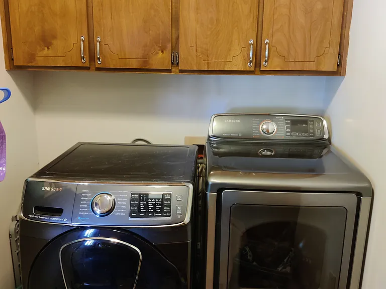 laundry room with storage and top load washer and a dryer. Note: appliances will stay in the house for renter to use (the front load washer was replaced with a top loader).