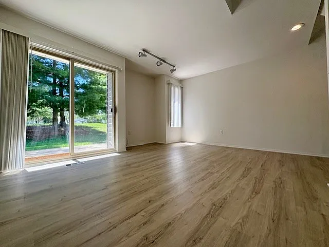 family room with glass door to patio and treed rear yard. Niche with track lighting