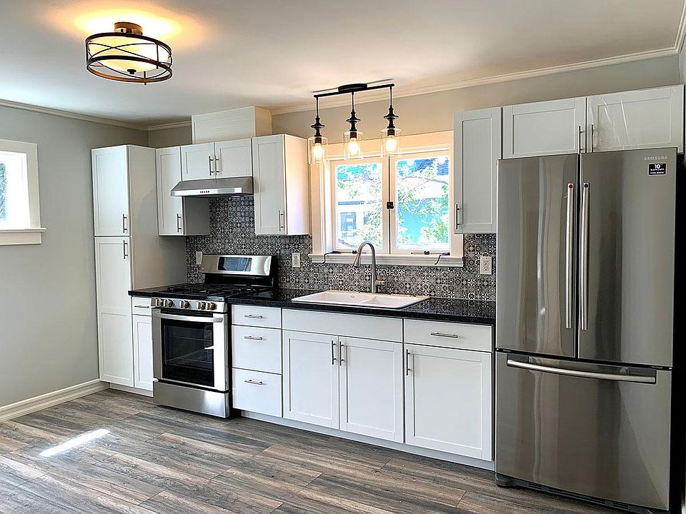 View of the spacious kitchen with fresh paint, new tile, fixtures, appliances, hardwood flooring, and cabinets.