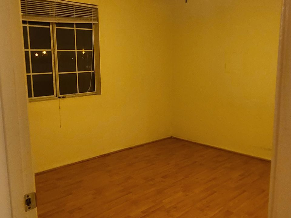 Bedroom east/south wall. Linoleum floor, ceiling fan.