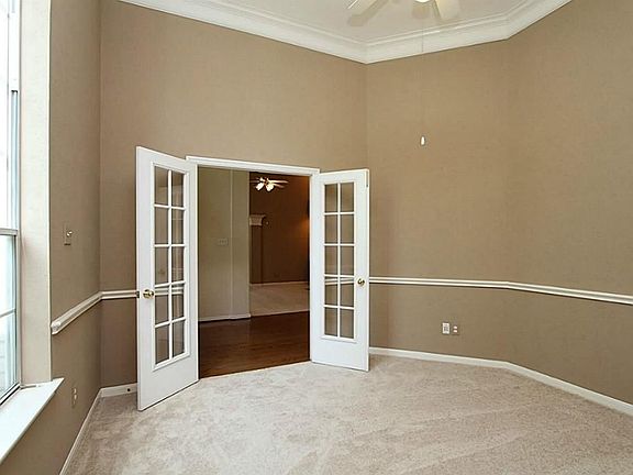 French doors lead into a beautiful study with vaulted ceilings and a floor to ceiling window