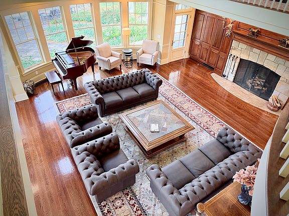 View of the richly decorated great room with seating for up to seventeen, a massive stone fireplace, and a grand piano.