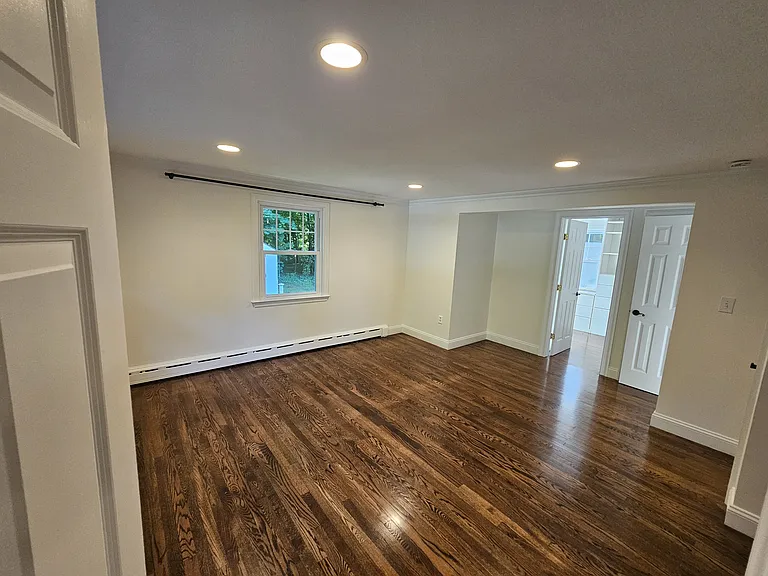Master bedroom with hardwood floors, recessed lighting, and natural light.