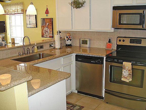 Kitchen with granite counters, stainless appliances and white cabinets.