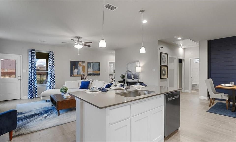 Kitchen with open floor plan, white cabinetry, pendant lighting, light wood-style flooring, and stainless steel dishwasher