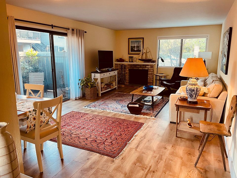 The open floor plan features hardwood/lvp flooring, glass doors opening out to a sunny patio, and a working, wood burning fireplace.