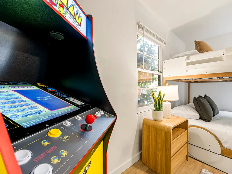 Fun and family-friendly bunk room featuring a queen-over-queen bunk bed, twin trundle, arcade game, and plenty of space for kids to unwind and enjoy.
