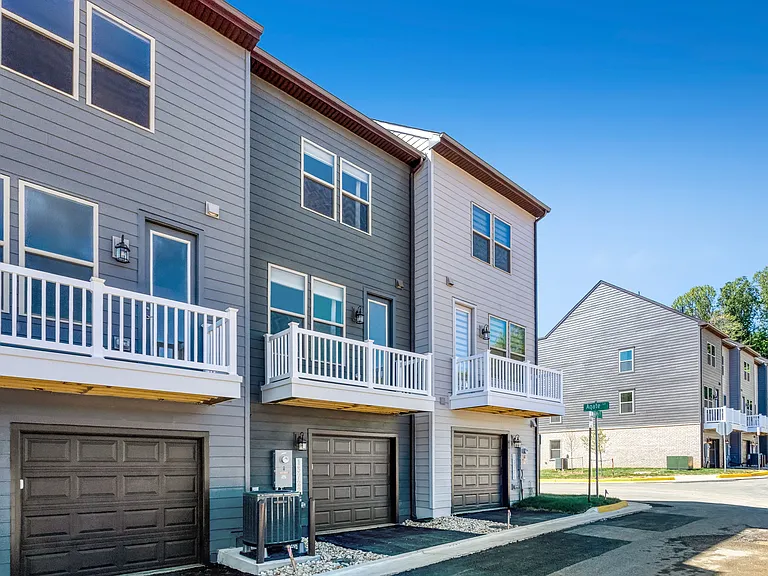 Rear view of the townhome highlighting outdoor space, garage access, and modern exterior design.