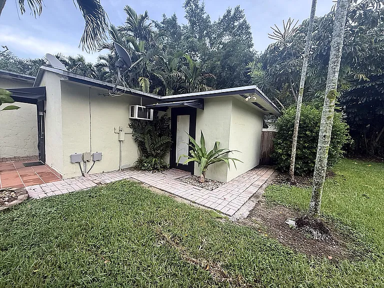 Additional exterior view of Palm Grove Cottage showing the walkway, landscaped yard and separate cottage setting.