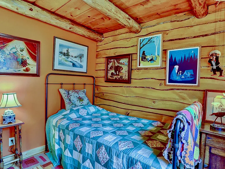 Guest Bedroom with Charles Rogers wrought iron twin bed and pop-up trundle, live edged wood paneling, and paintings and lithographs.