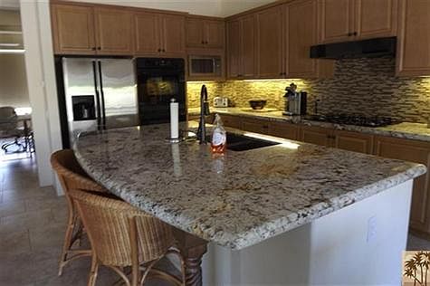 Slab granite island kitchen with glass tile backsplash, stainless steel appliances - open to great room