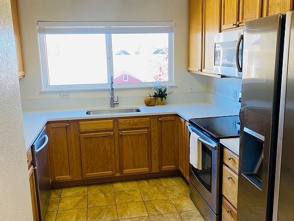 Updated kitchen with white quartz countertops, stainless steel appliances including a dishwasher and dual access refrigerator
