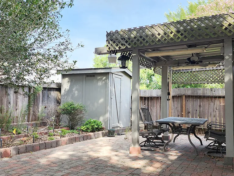Covered patio with complementary furnished patio table and chairs. Shed in background for outdoor storage.