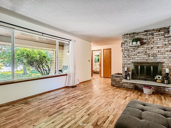 Living room with a large front picture window with a lovely wood burning fireplace.>