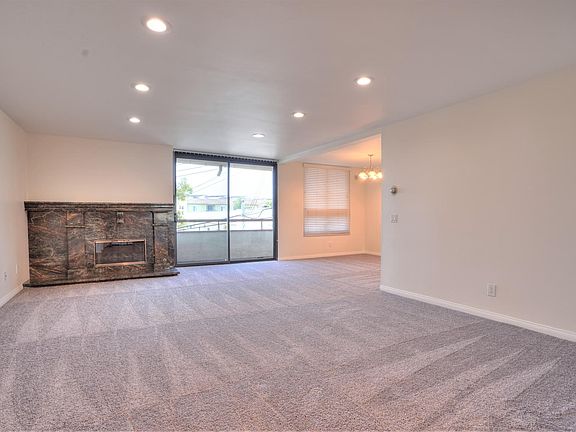 Living Room view with fireplace, balcony, dining area. New carpet and freshly painted.