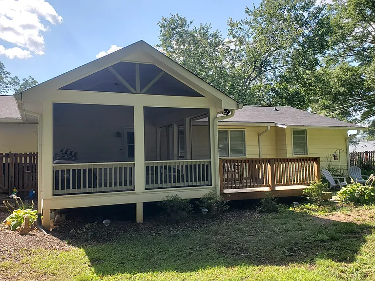 Screened in porch with tile flooring, ceiling fan and side deck.