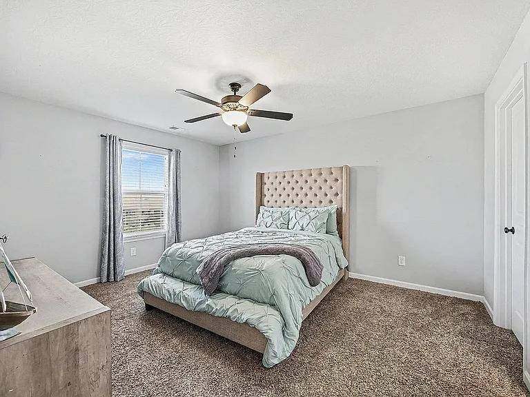 Spacious primary suite with plenty of natural light, plush carpeting, and a relaxing atmosphere.