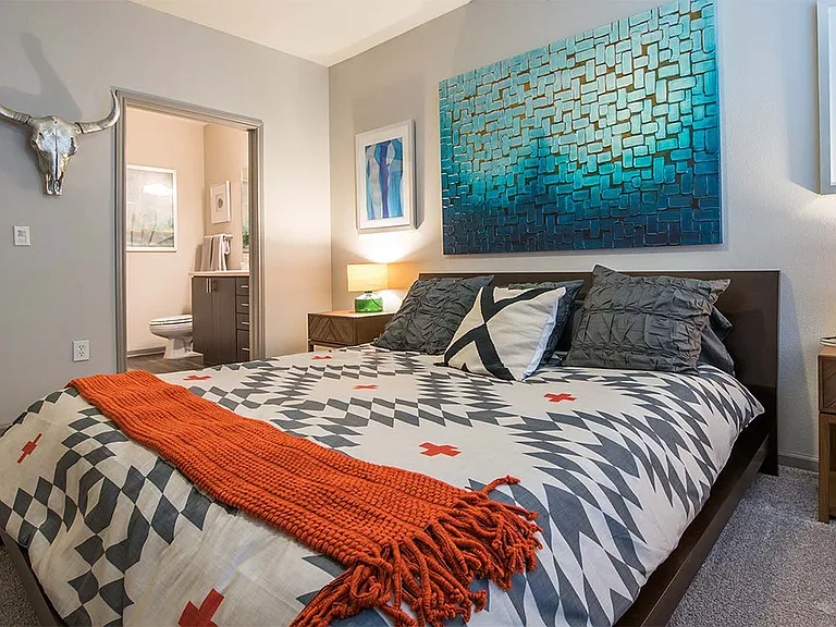 Spacious apartment bedroom with carpeted floors overlooking bathroom.