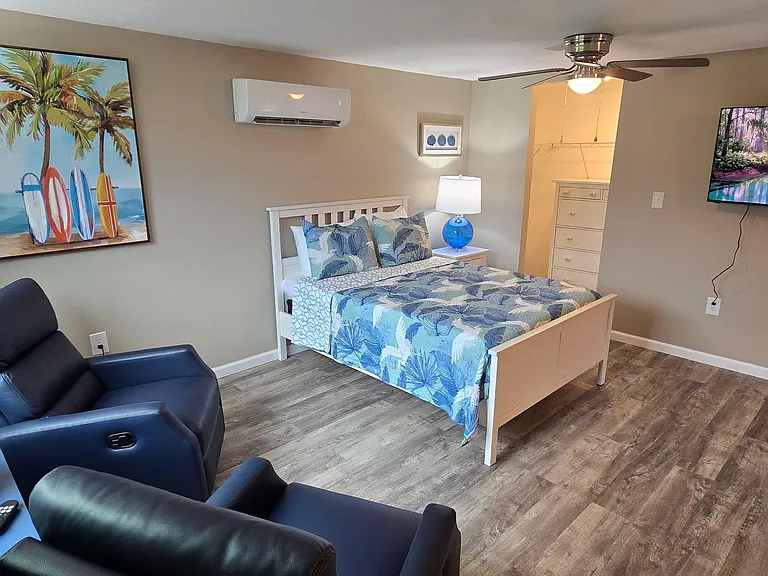 Furnished bedroom with a full bed, recliner seating, wall-mounted TV, and private mini-split A/C for comfort.