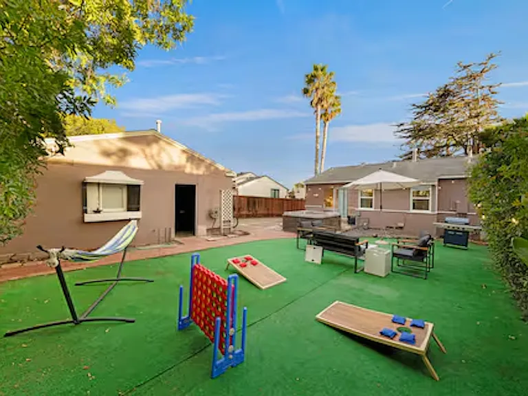 Enjoy the private outdoor space featuring a spacious hot tub that seats 6_8 guests and a cozy fire pit, perfect for relaxing after a beach day. The area also includes a barbecue grill and lawn games, ideal for outdoor dining and fun.