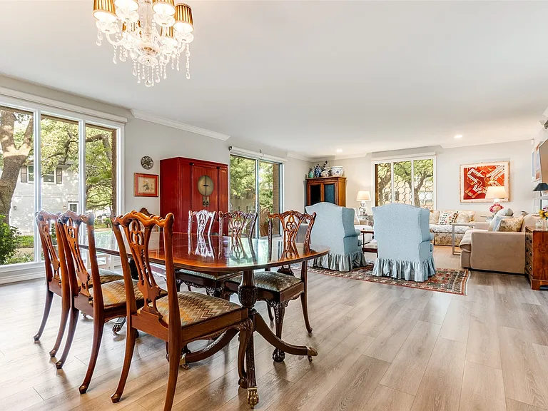 Open-concept living area featuring wood-finish flooring, a crystal chandelier, recessed lighting, and large windows with abundant natural light