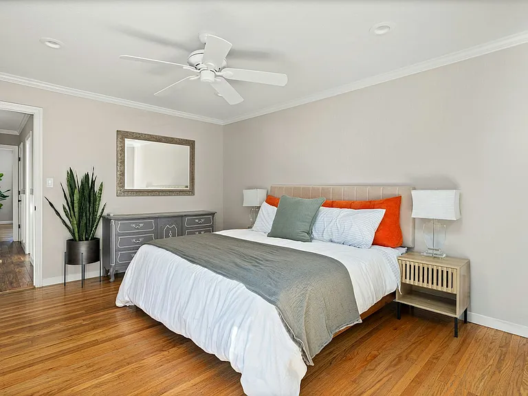 Spacious & serene primary suite unwind in this bright, airy bedroom with warm hardwood floors, soft natural light, and plenty of room to relax and recharge.