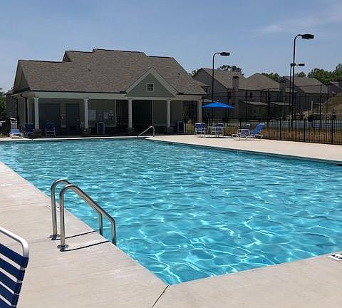 large neighborhood pool with covered areas next to tennis courts