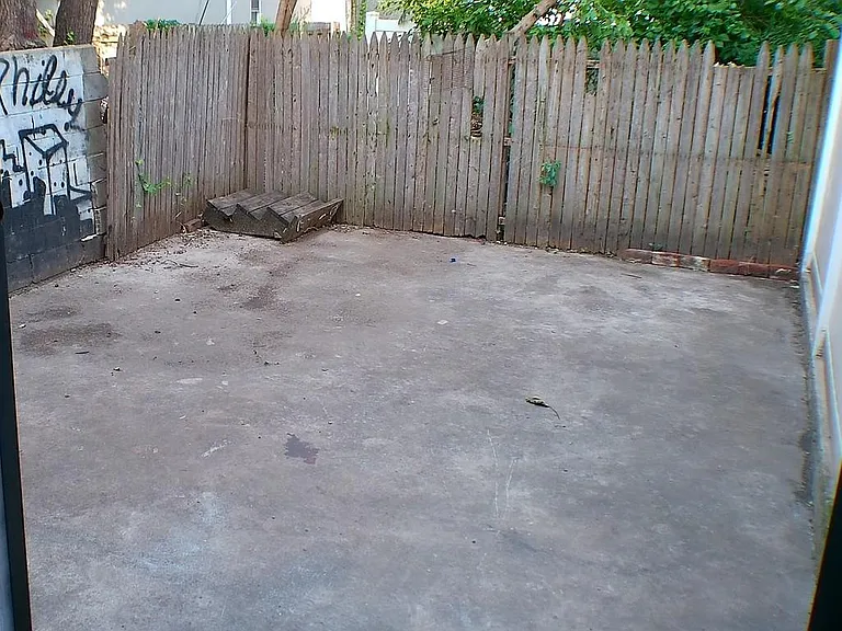 Fenced outdoor patio with a concrete pad, ideal for grilling, outdoor seating, or secure bike storage.