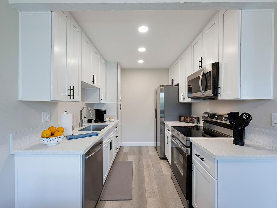 Galley kitchen with newer white shaker cabinets and stainless appliances