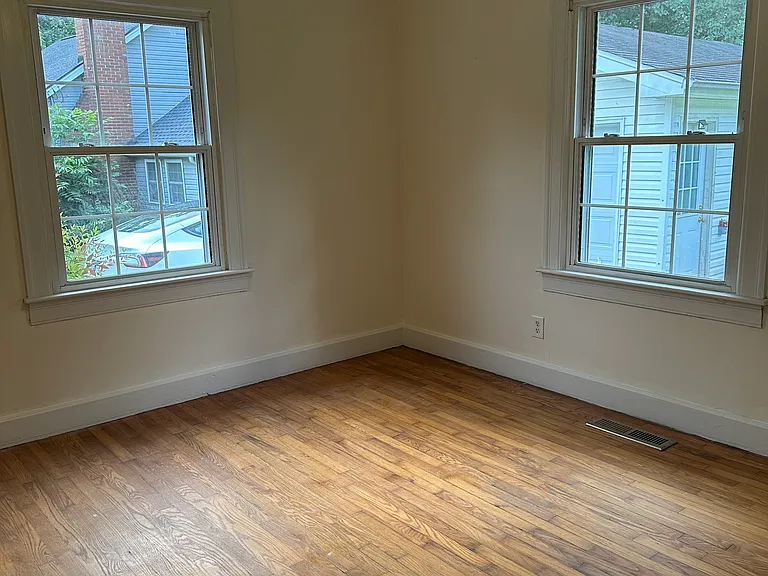 Bedroom 1 with 2 windows for cross ventilation. Room has hardwood floor and ceiling fan.