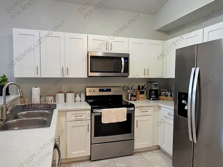 Enjoy culinary convenience in this sleek, modern kitchen featuring high-quality stainless steel appliances, ample white cabinetry for organized storage, and a functional breakfast bar that keeps the space connected to the rest of the home