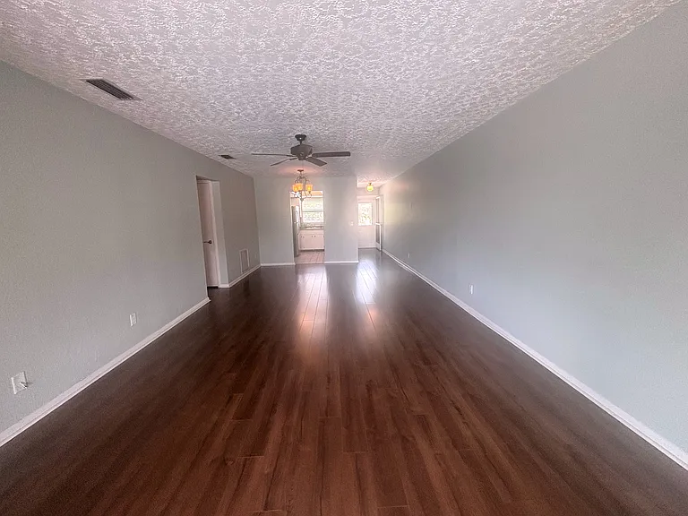 View of living room from sliding glass doors looking back toward dining area and then kitchen just behind. Front door is to the far right with the light coming in :)
