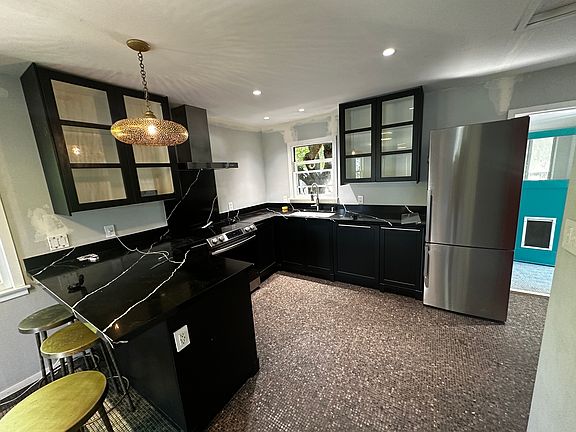 Kitchen with dishwasher, induction range, oven, fridge, freezer, garbage disposal and storage.