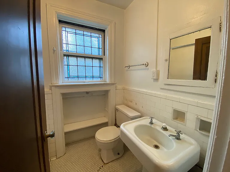 The bathroom blends functionality with character, highlighted by the built in storage, beautiful privacy window, and the pedestal sink.
