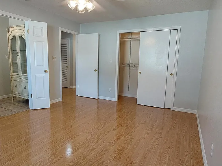 In primary bedroom facing closet, entrance, and bathroom. Closet is lit, has adjustable shelves, and is longer than the opening is wide.