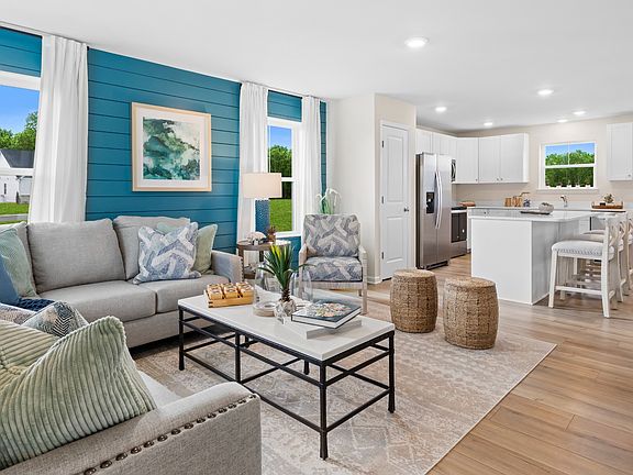 Open main level living room and kitchen in a DRB Homes Whitehall model home at The Village of Colle