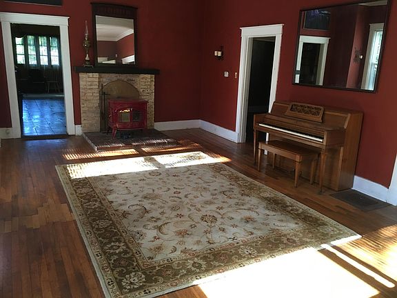 Open living room with piano and wool rug furnished.