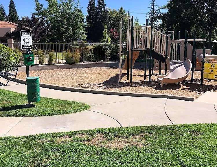 Play area in a parklike setting for the kids located next to the gated pool area.