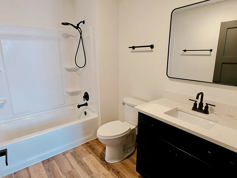 Primary bathroom features vanity, toilet, towel storage and shower/tub combo.