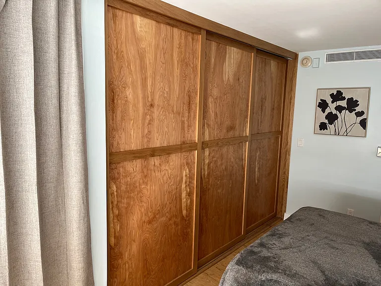 Triple track sliding doors open to join ocean view bedroom to living room space.