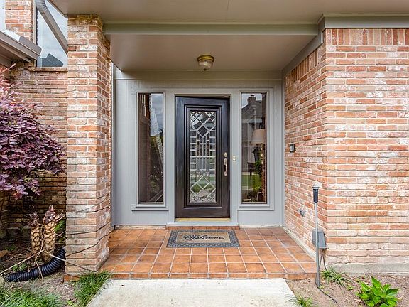 A covered saltillo tiled front porch and beautiful wood and leaded glass front door with side panels welcome you in to this beau