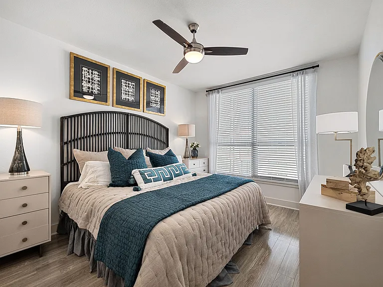 Bedroom with statement headboard, ceiling fan, and large window